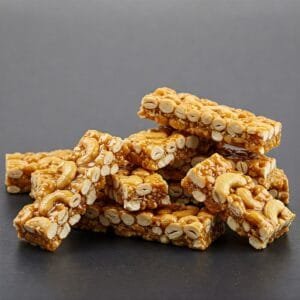 a stack of zestbites cashew chikki bars on a wooden board